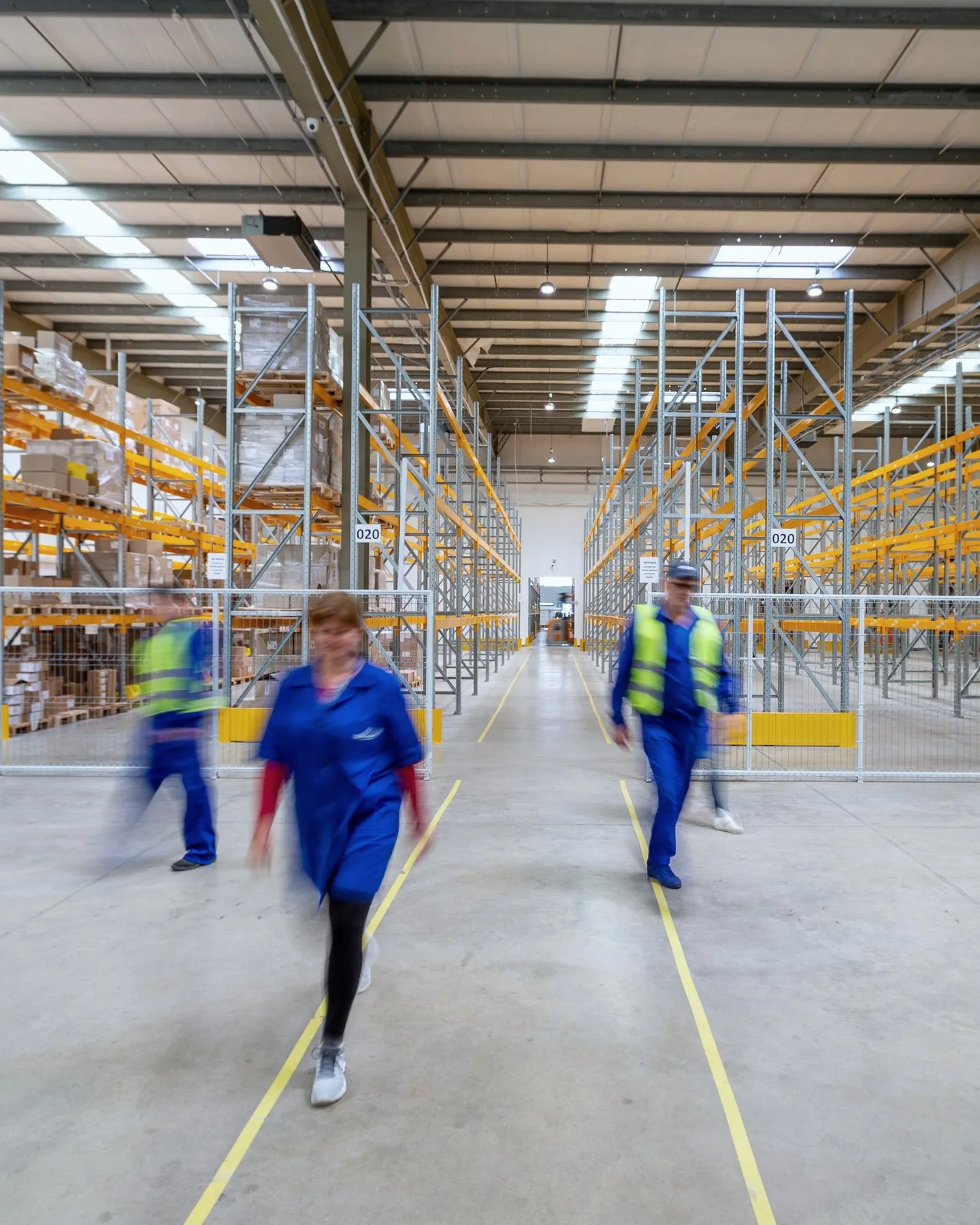 Warehouse staff crossing the floor between pallet racking aisles
